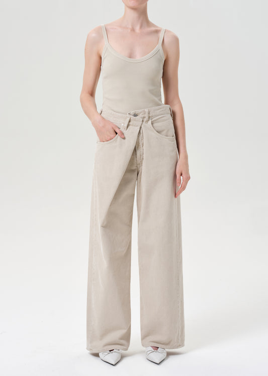 Person wearing a beige tank top and wide-leg pants on a white background