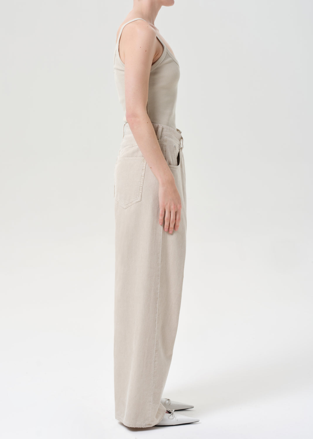 Person wearing a beige sleeveless top and pants on a white background