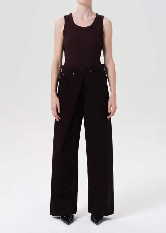 Person wearing a black sleeveless top and wide-leg pants on a white background