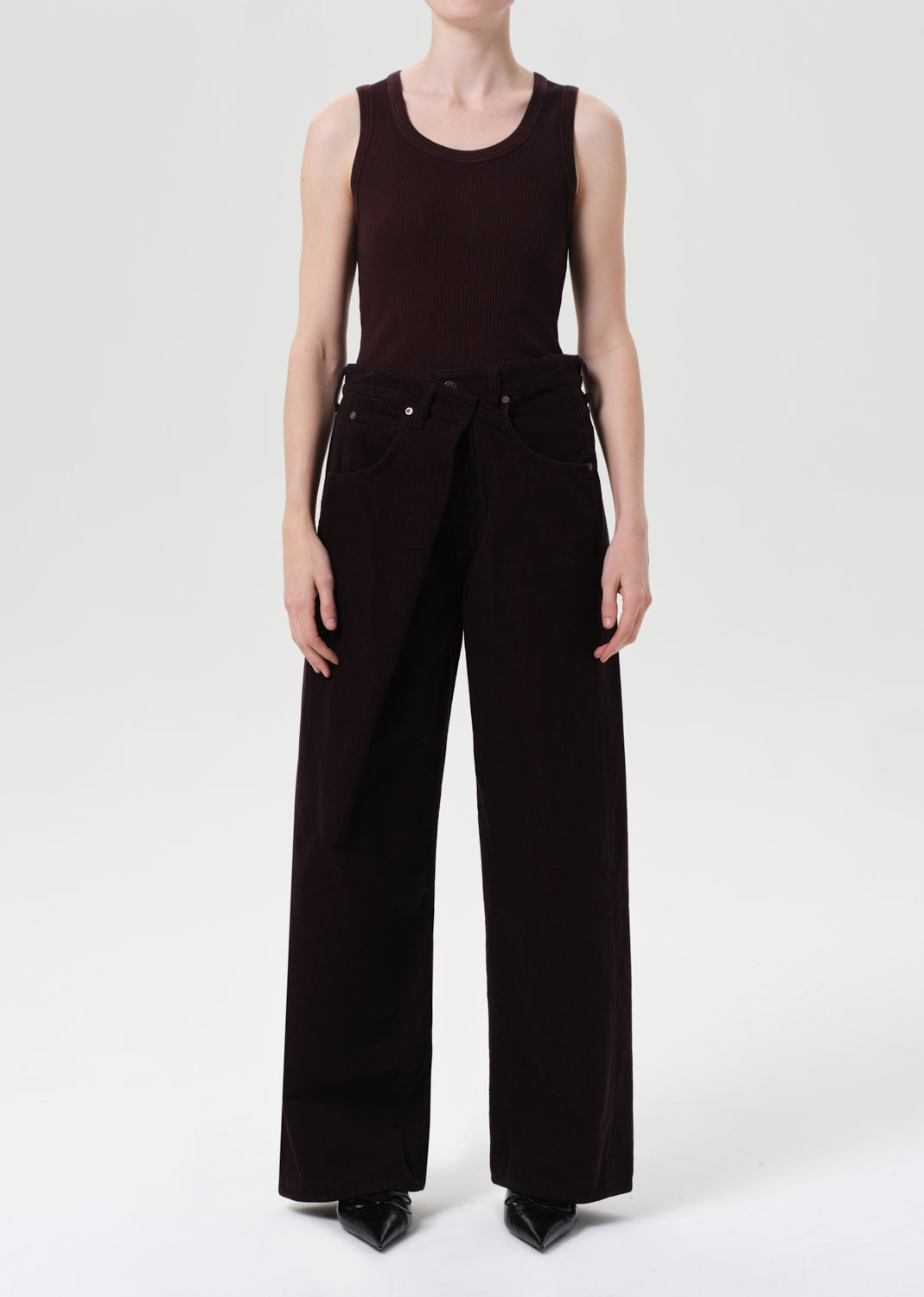 Person wearing a black sleeveless top and wide-leg pants on a white background