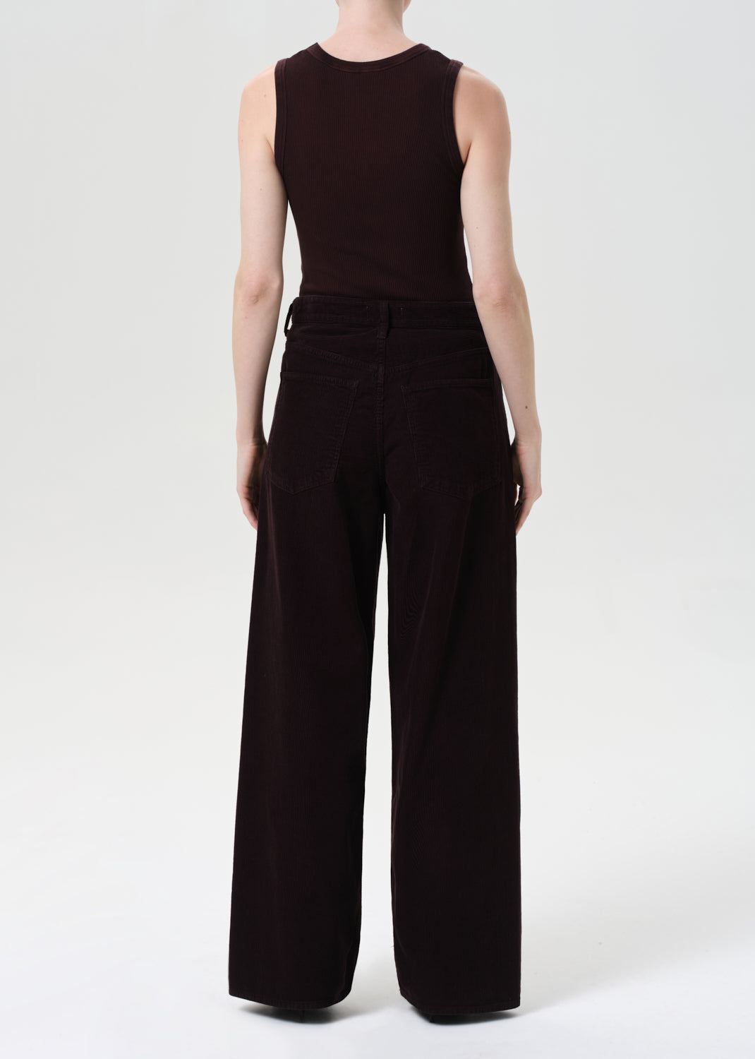 Person wearing a black sleeveless top and wide-leg pants on a white background