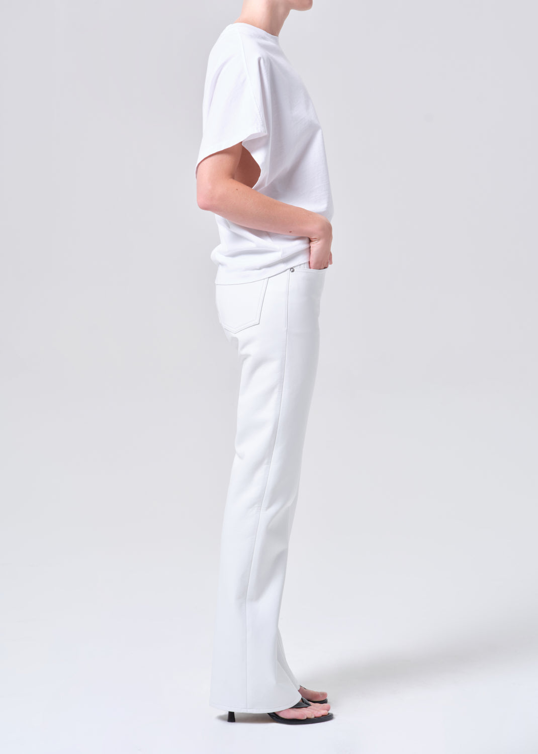 Person wearing a plain white t-shirt and pants on a light gray background