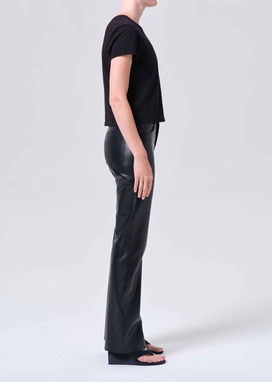 Person wearing a black t-shirt and shiny black pants on a white background