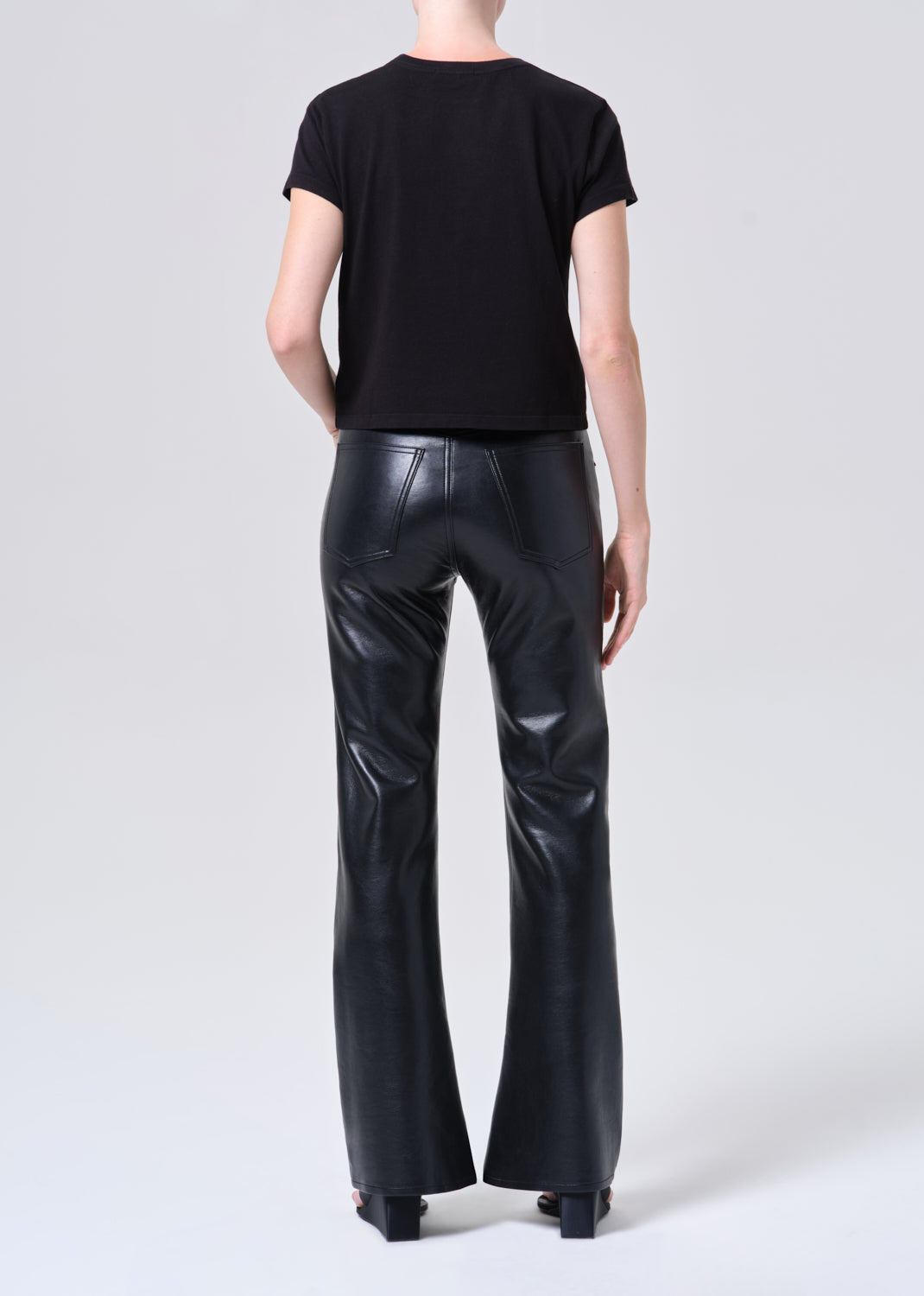 Person wearing black leather pants and a black t-shirt on a white background