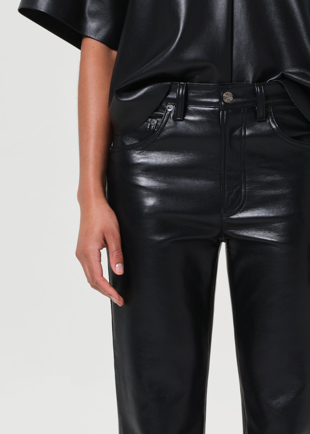Person wearing black leather pants on a plain background