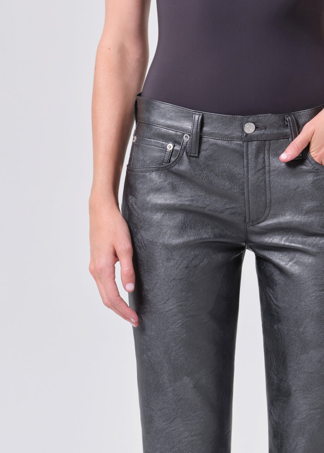 Person wearing shiny black pants on a plain background