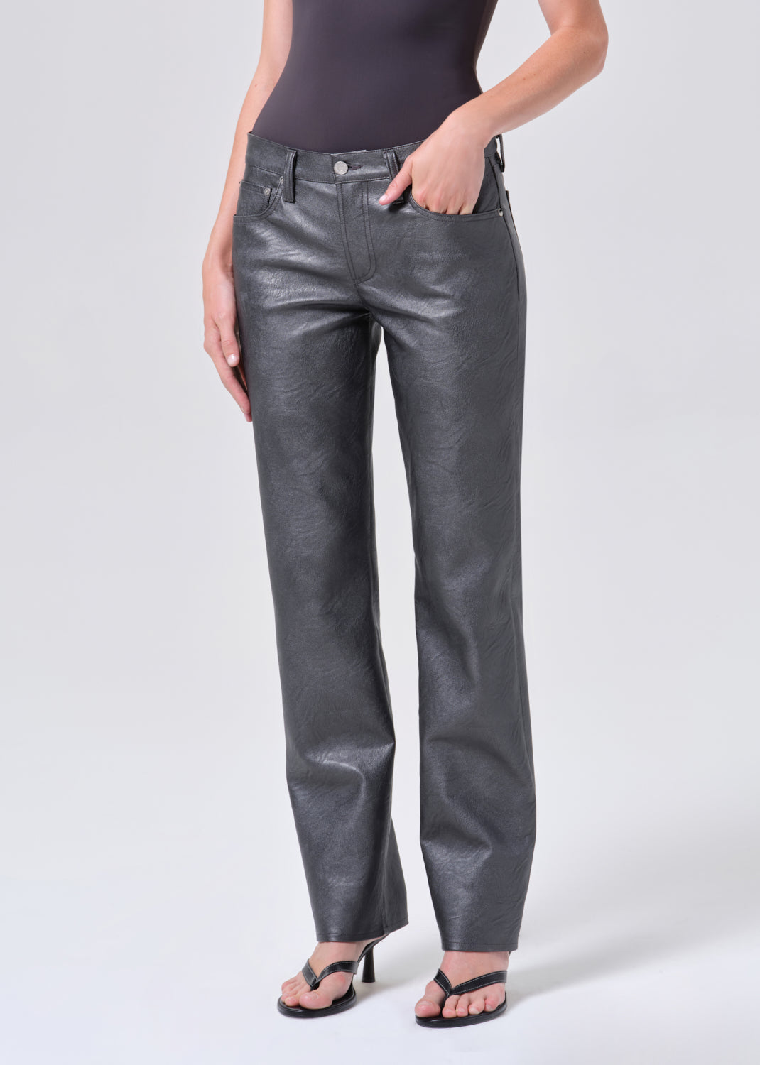 Person wearing shiny gray pants on a white background