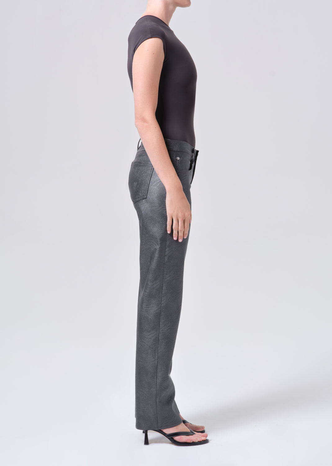 Person wearing gray pants and a dark top on a white background