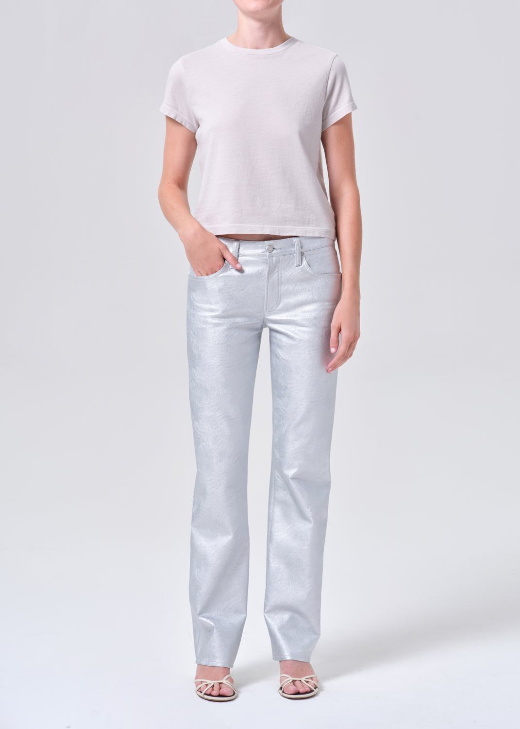 Person wearing light gray t-shirt and silver pants on a white background