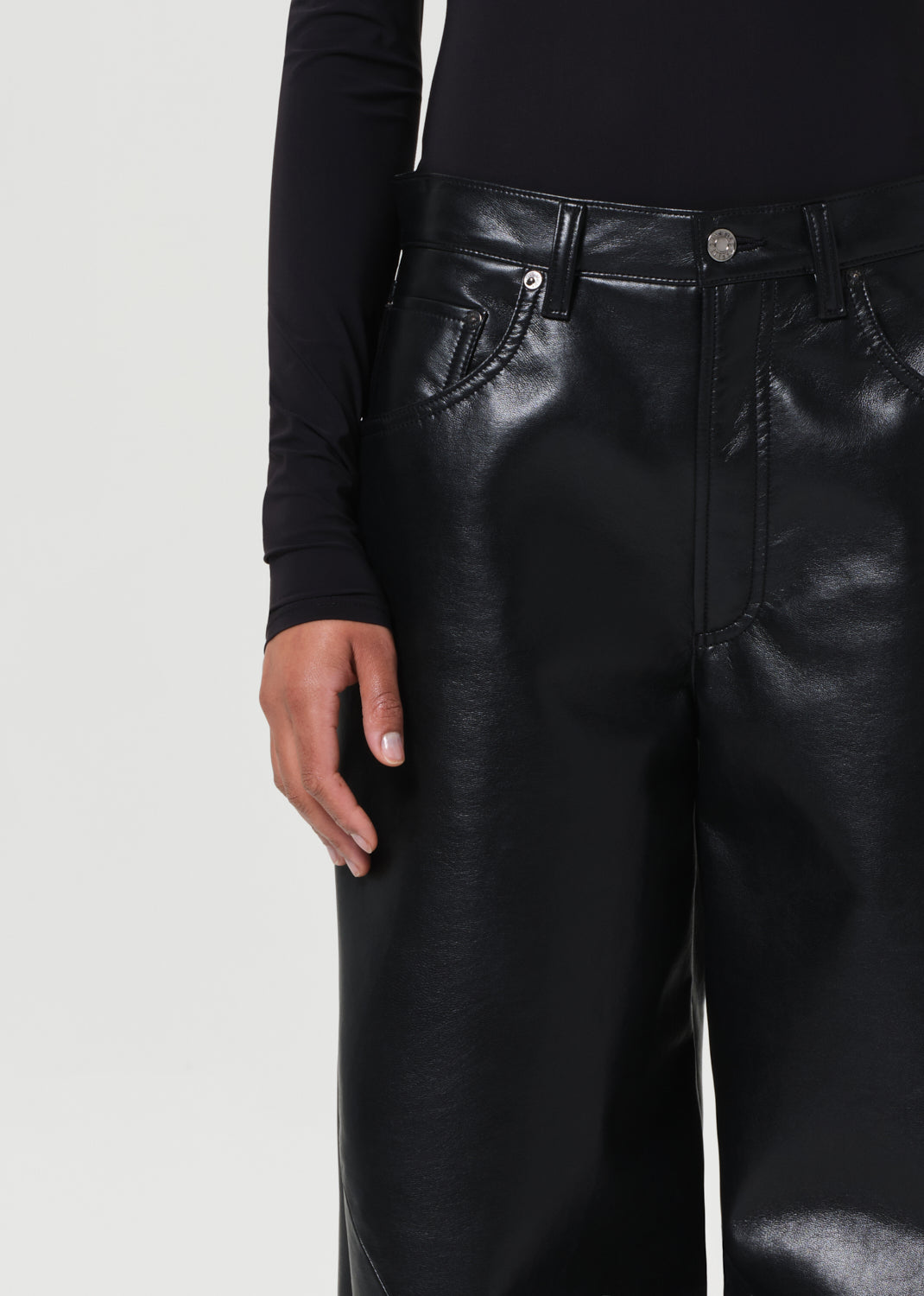 Black leather pants worn by a person on a light gray background