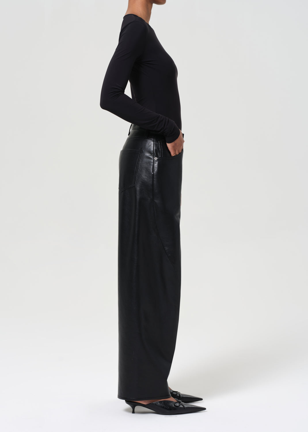 Person wearing black leather pants and a black top on a white background