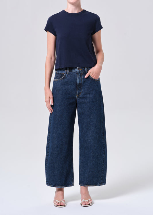 Person wearing a navy t-shirt and dark blue wide-leg jeans on a white background