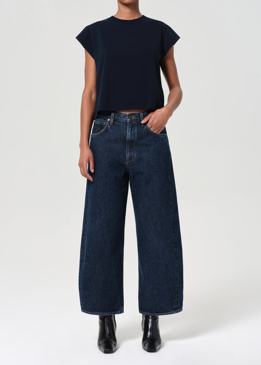 Person wearing a black top and dark blue jeans on a white background