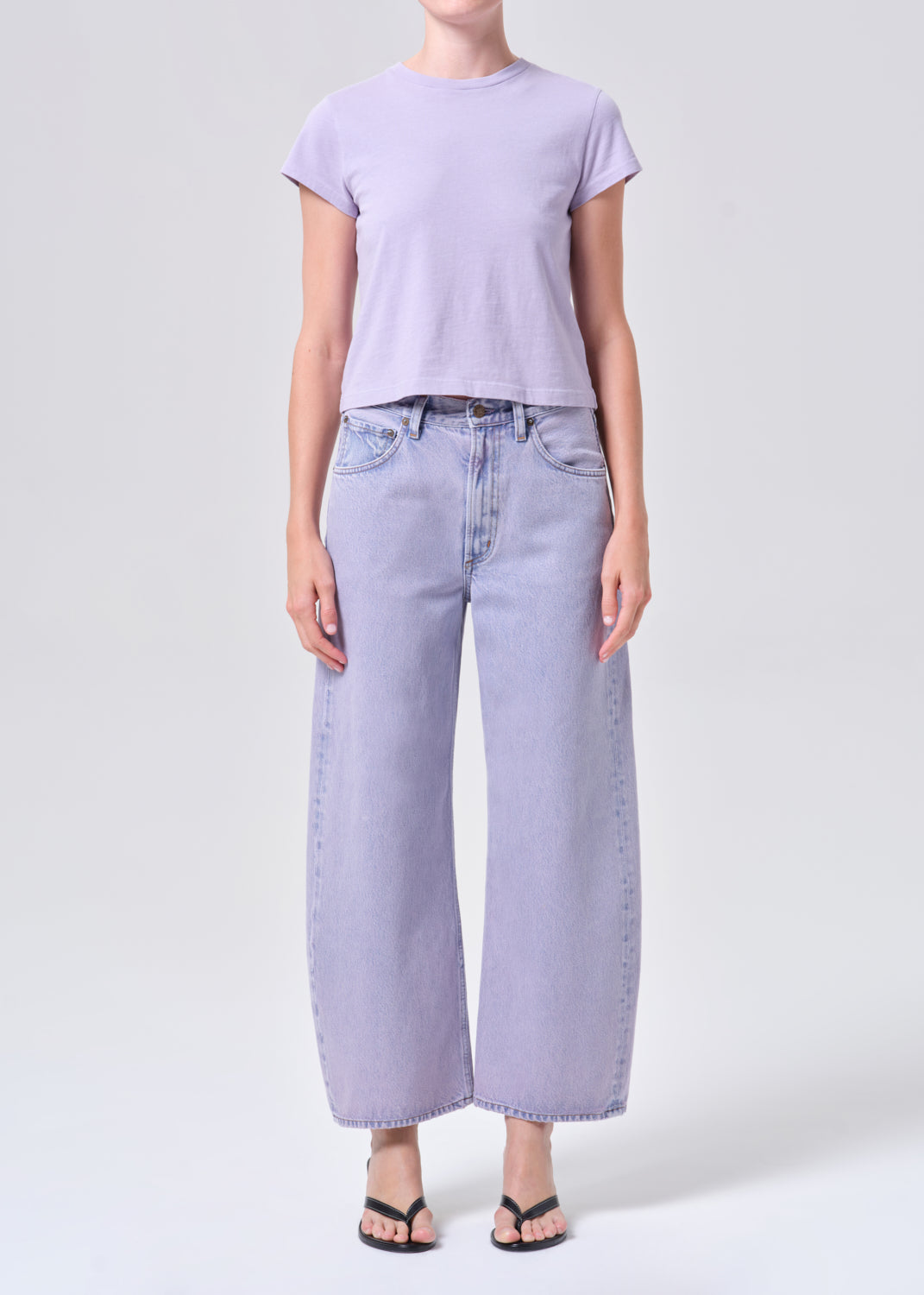 Person wearing a light purple t-shirt and wide-leg jeans on a white background