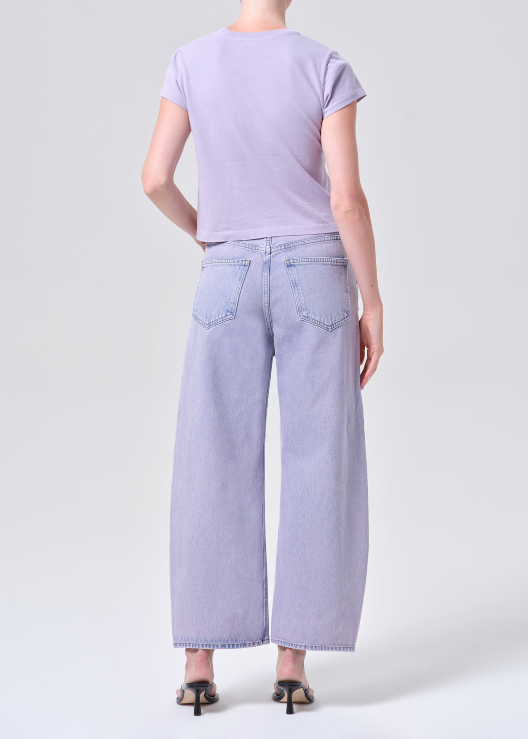 Person wearing a light purple t-shirt and wide-leg jeans on a white background