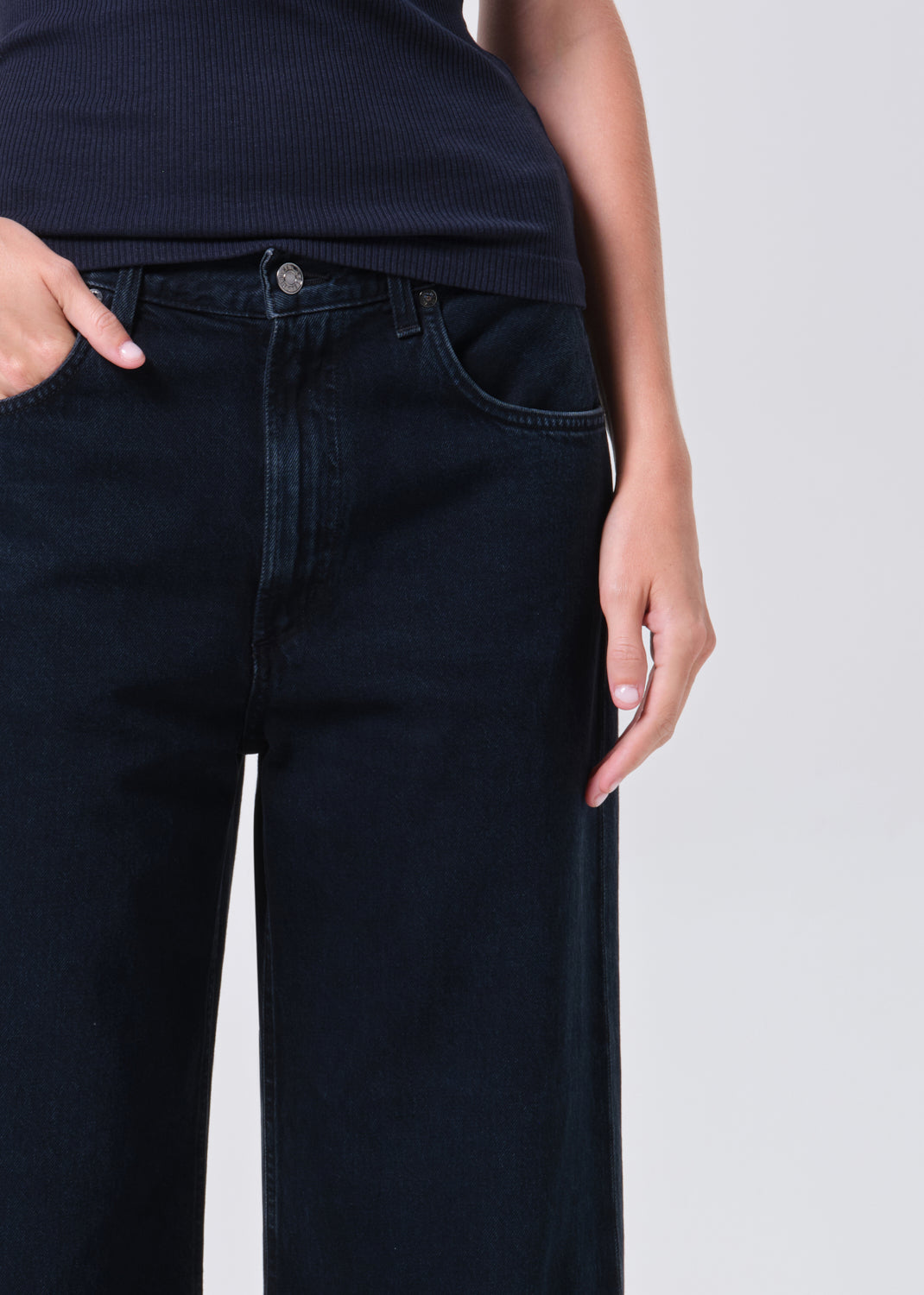 Person wearing black jeans on a plain background