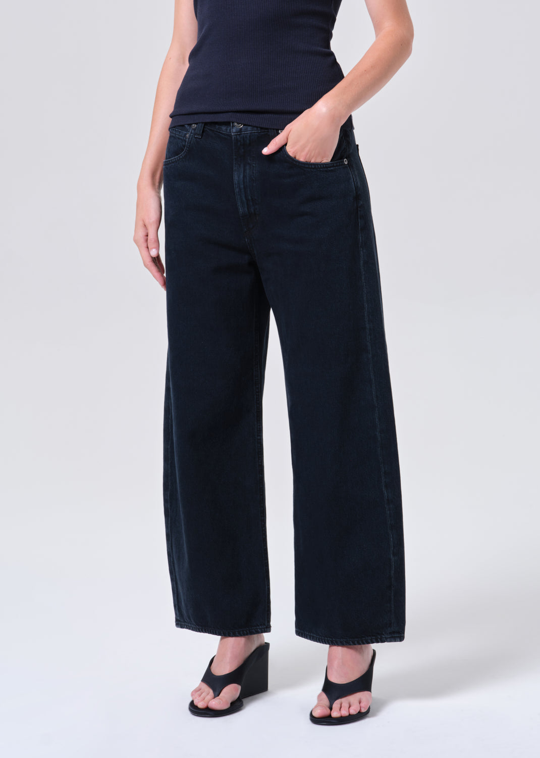 Person wearing dark blue wide-leg jeans on a white background