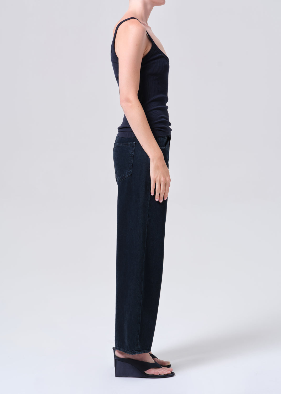 Person wearing a black sleeveless top and wide-leg pants on a white background