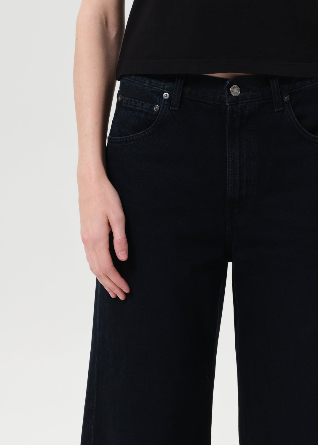 Person wearing black jeans on a light gray background
