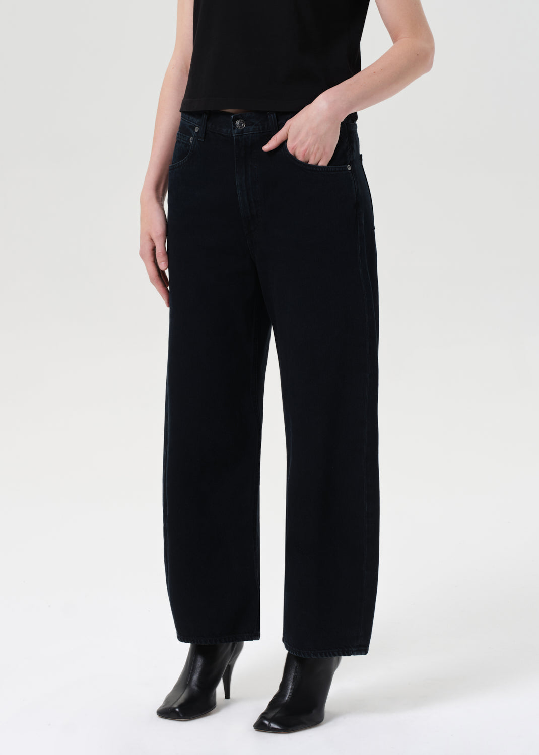 Person wearing black high-waisted jeans on a white background