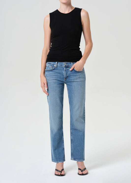 Person wearing a black sleeveless top and blue jeans on a white background