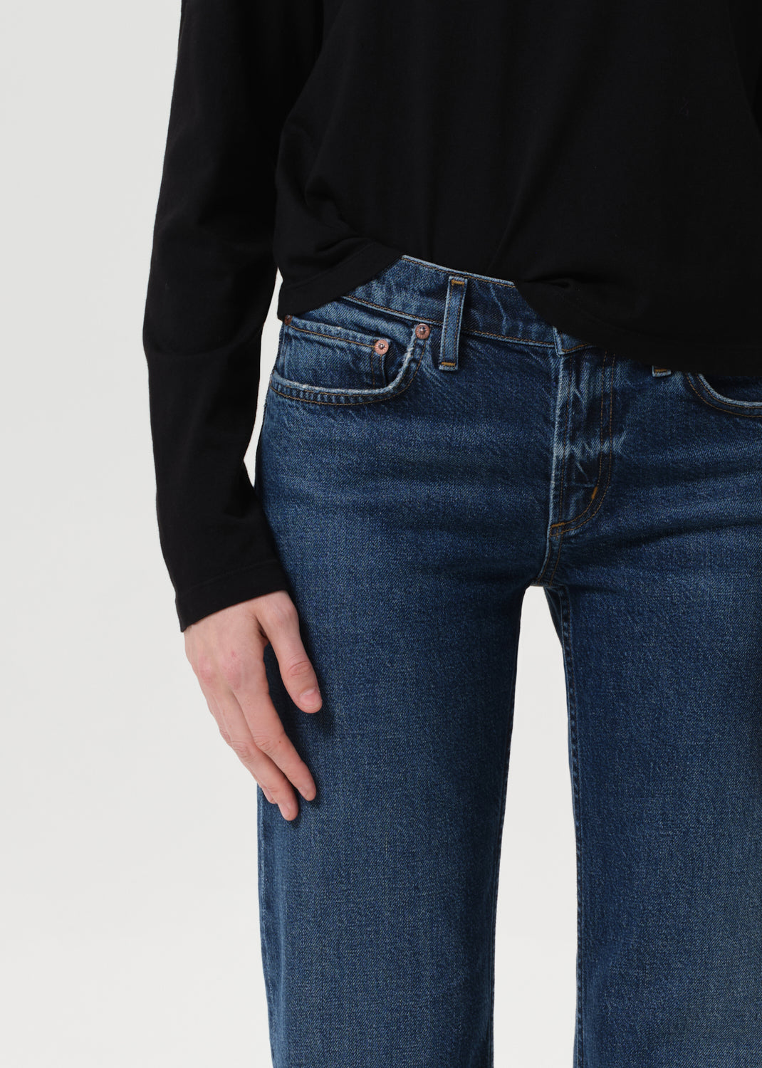 Person wearing blue jeans and a black long-sleeve shirt on a white background