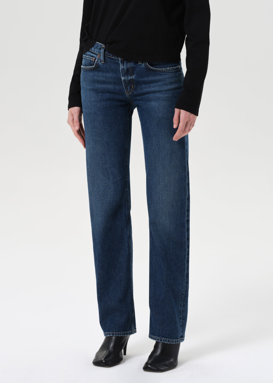 Person wearing blue jeans and a black top on a white background