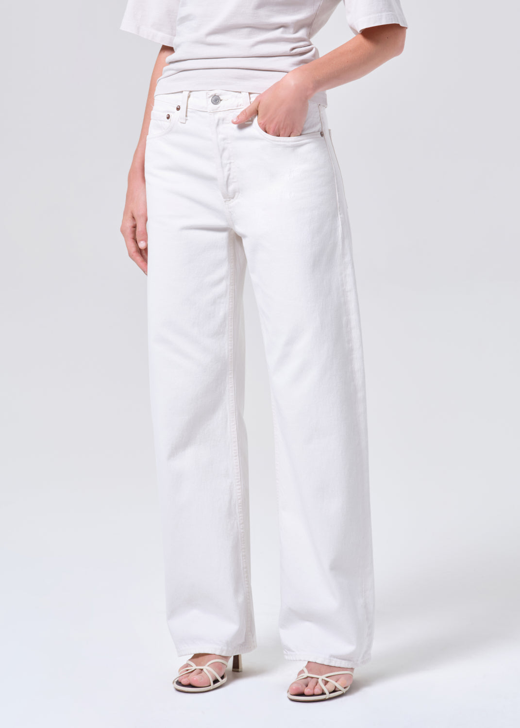 Person wearing white jeans on a plain background