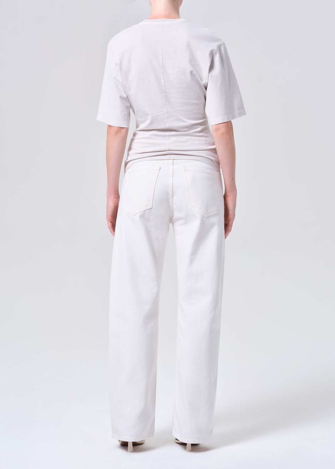 Person wearing a white t-shirt and wide-leg pants on a plain background