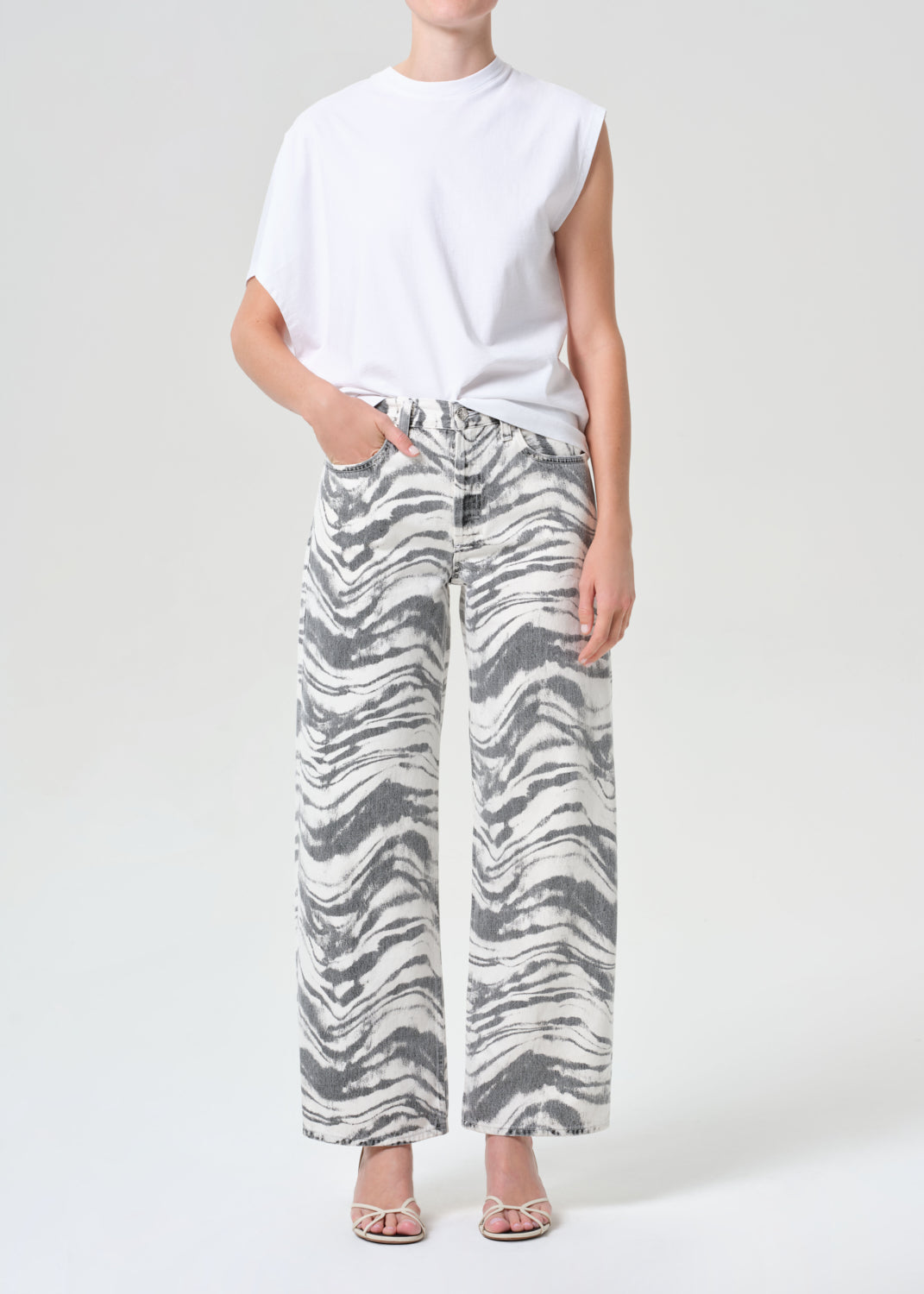 Person wearing a white sleeveless top and zebra print pants on a white background