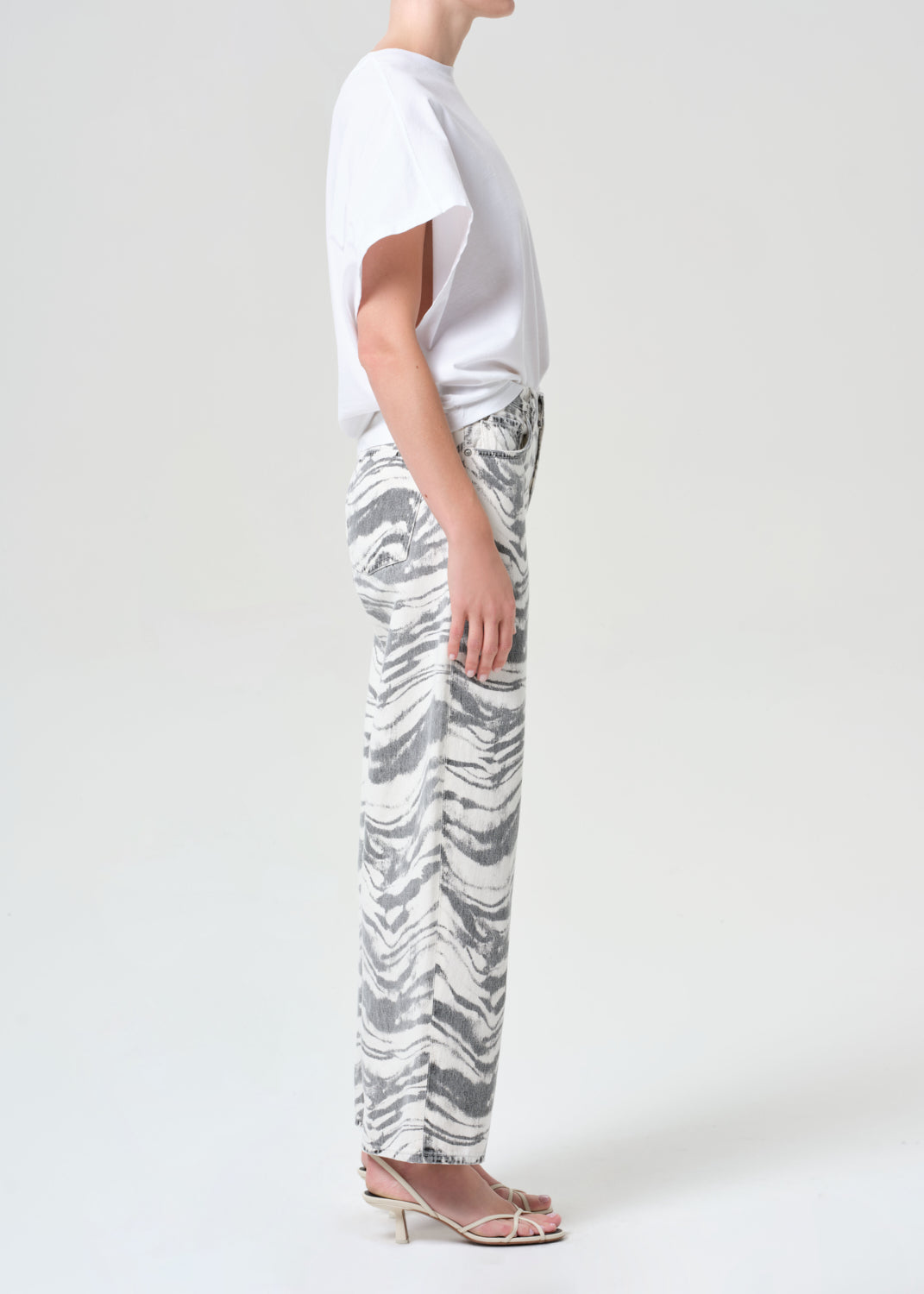 Person wearing a white top and patterned pants on a plain background