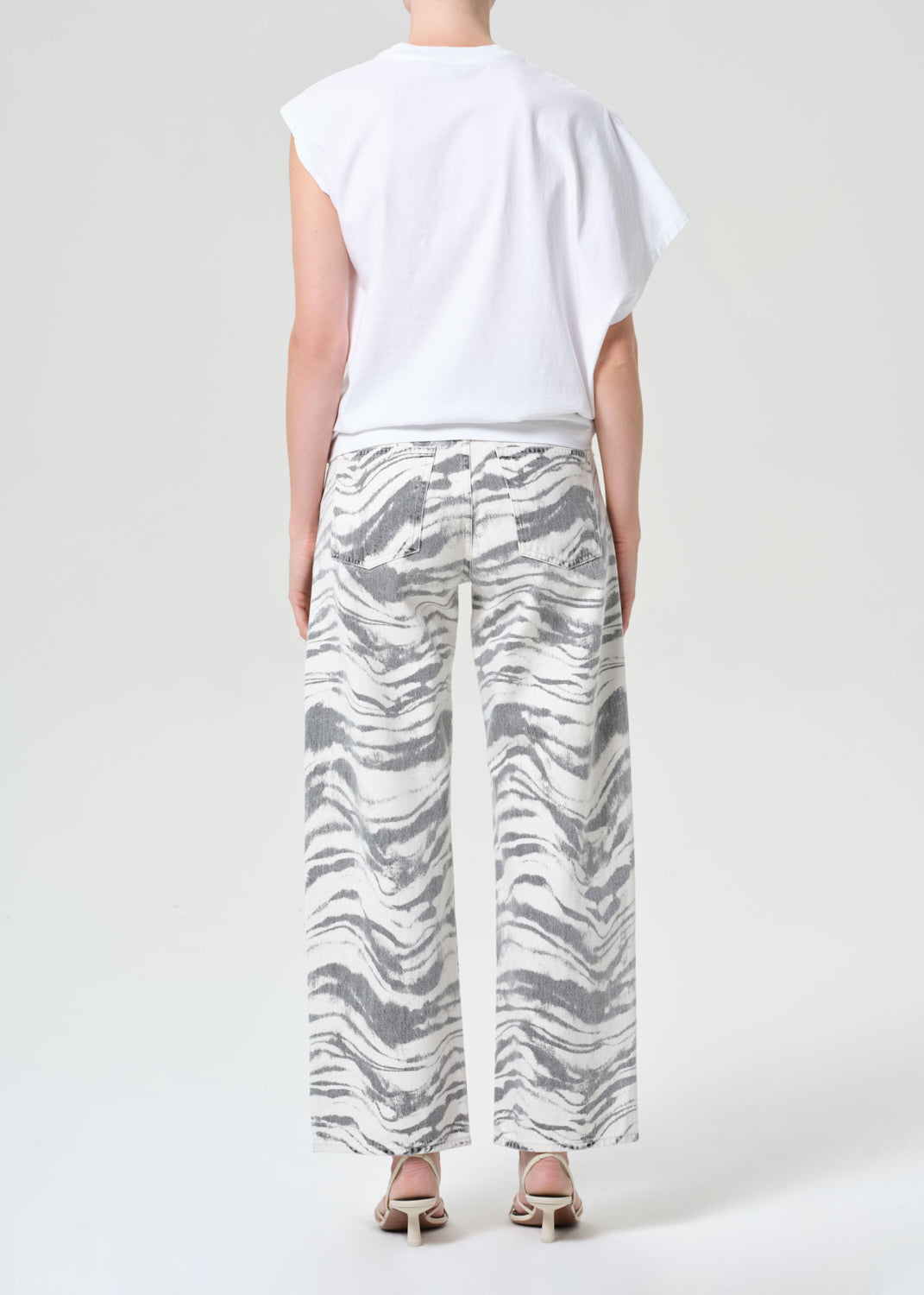 Person wearing a white top and zebra-striped pants on a plain background