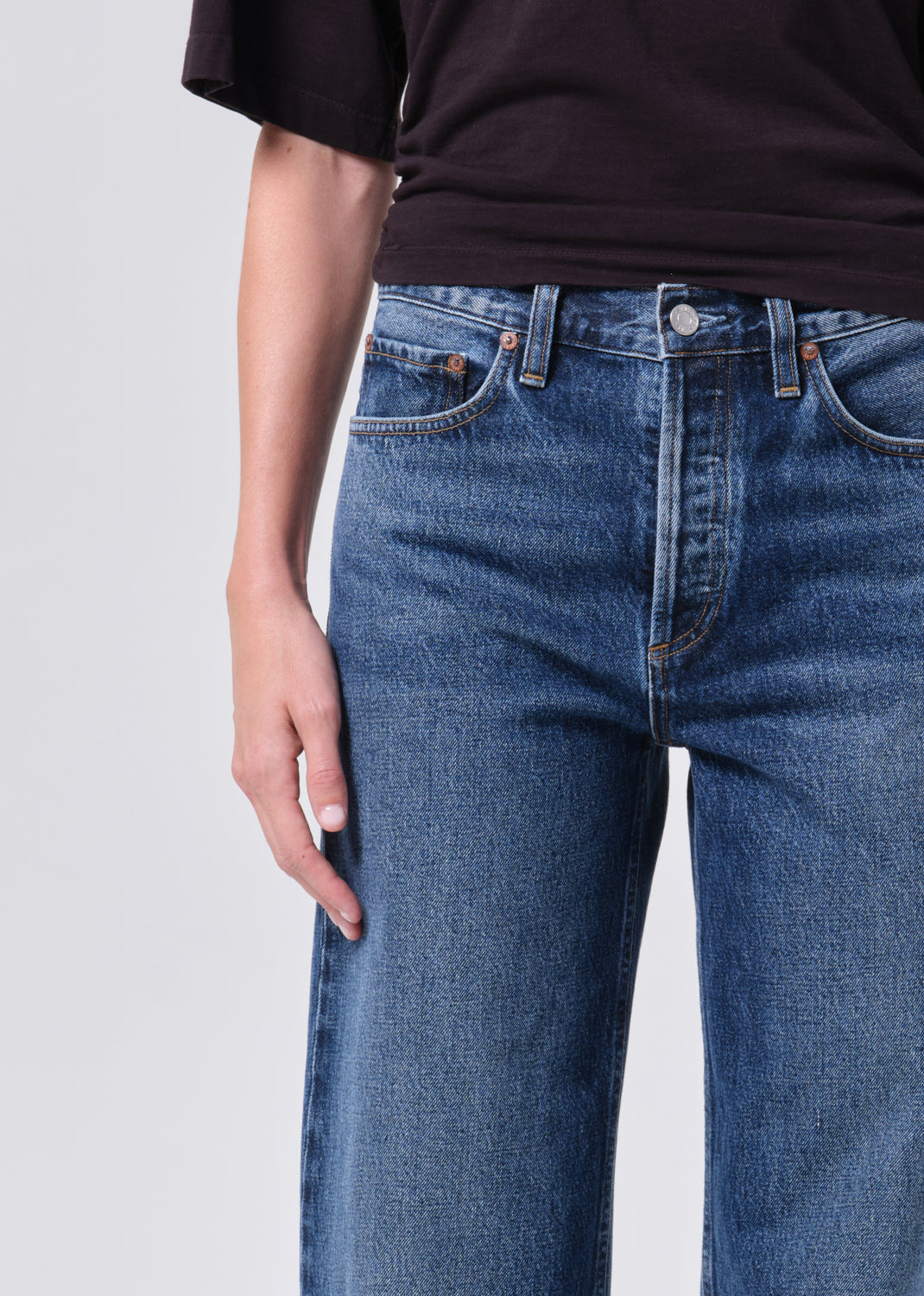 Person wearing blue jeans and a black shirt on a light gray background