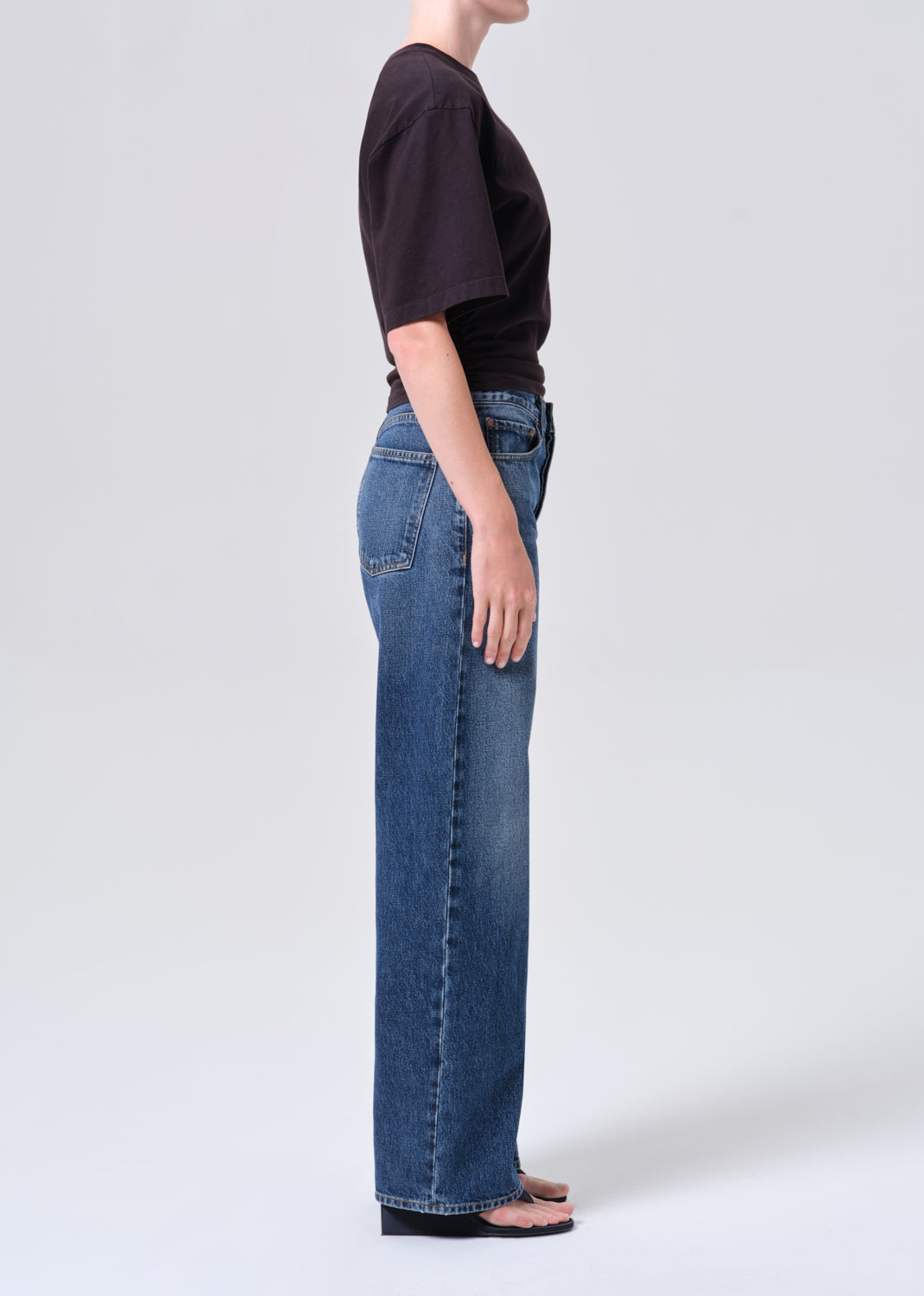 Person wearing blue jeans and a black top on a white background