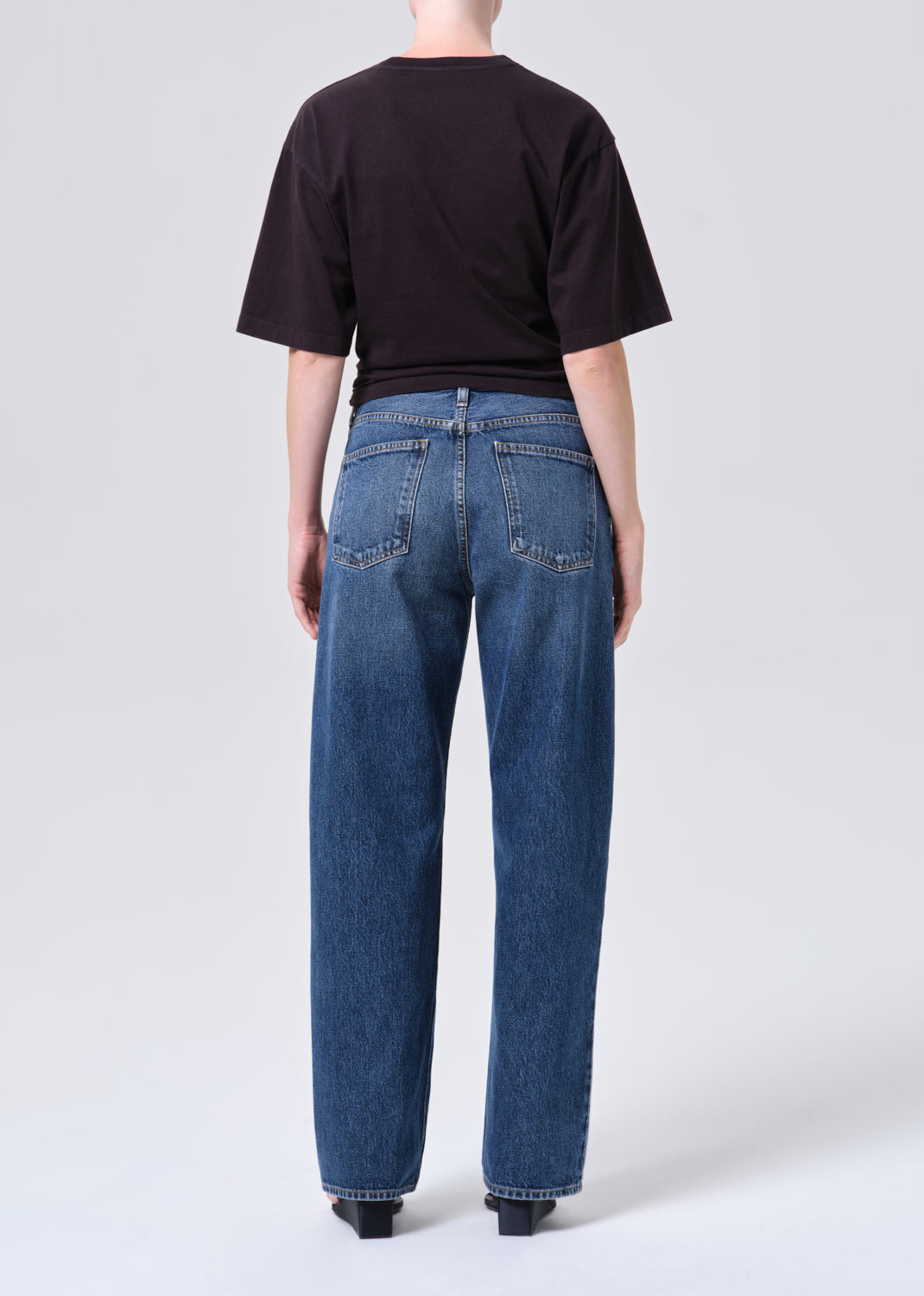 Person wearing blue jeans and a black t-shirt on a white background