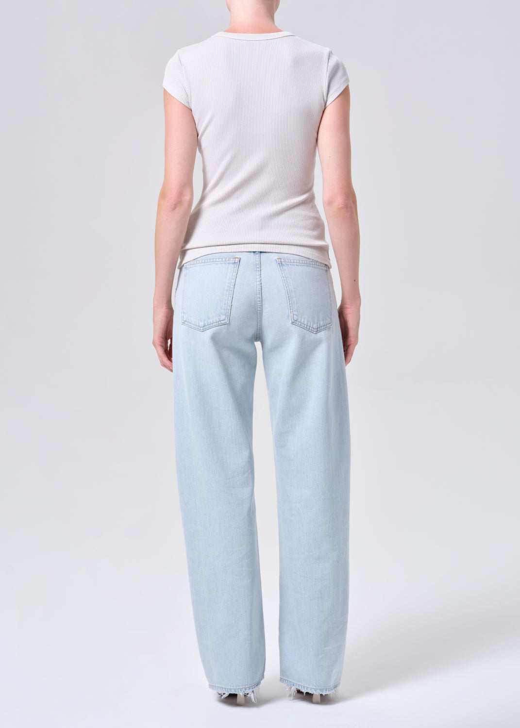 Person wearing light blue jeans and a white t-shirt on a plain background