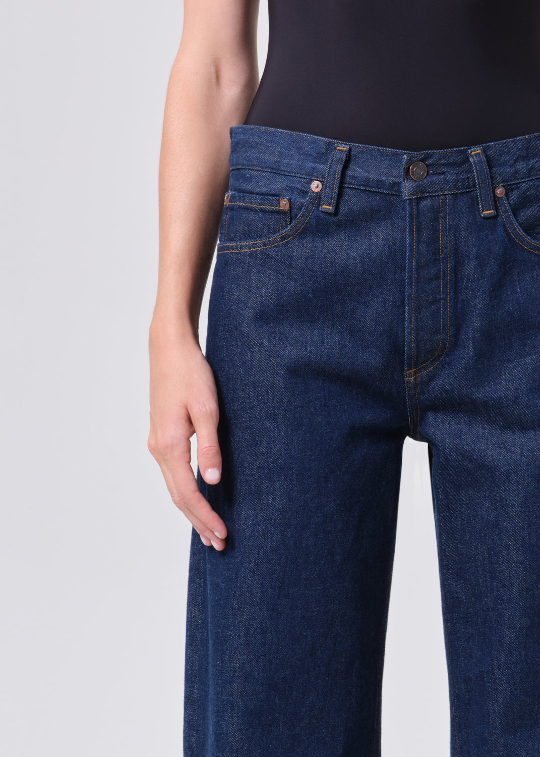 Person wearing dark blue jeans on a light gray background