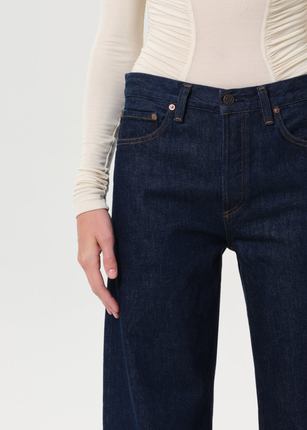 Person wearing dark blue jeans with a plain background