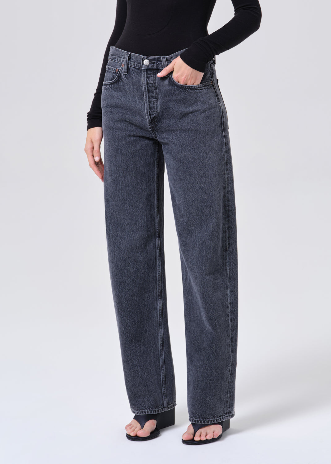 Person wearing dark blue jeans and a black top on a white background