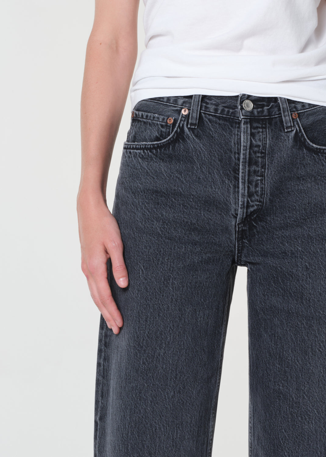 Person wearing dark blue jeans and a white shirt on a light gray background