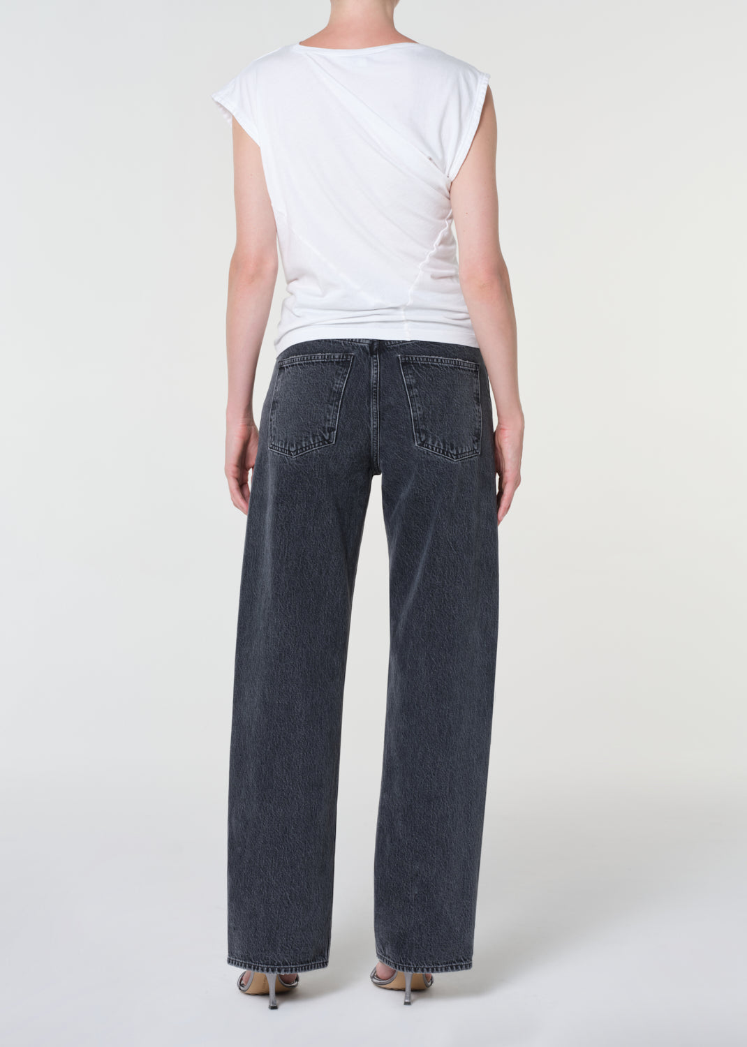 Person wearing a white t-shirt and dark blue jeans on a plain background