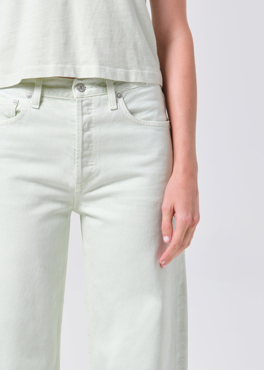White jeans worn by a person on a plain background