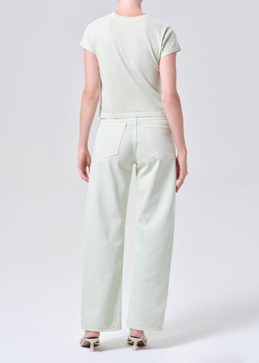 Person wearing a light green outfit with wide-leg pants on a white background