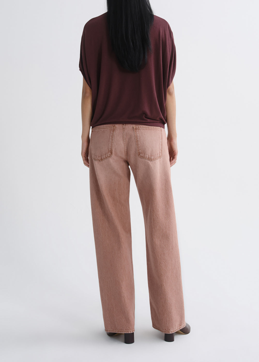 A model shown from the back wearing dusty rose wide-leg jeans and a dark burgundy short-sleeve top against a grey background.