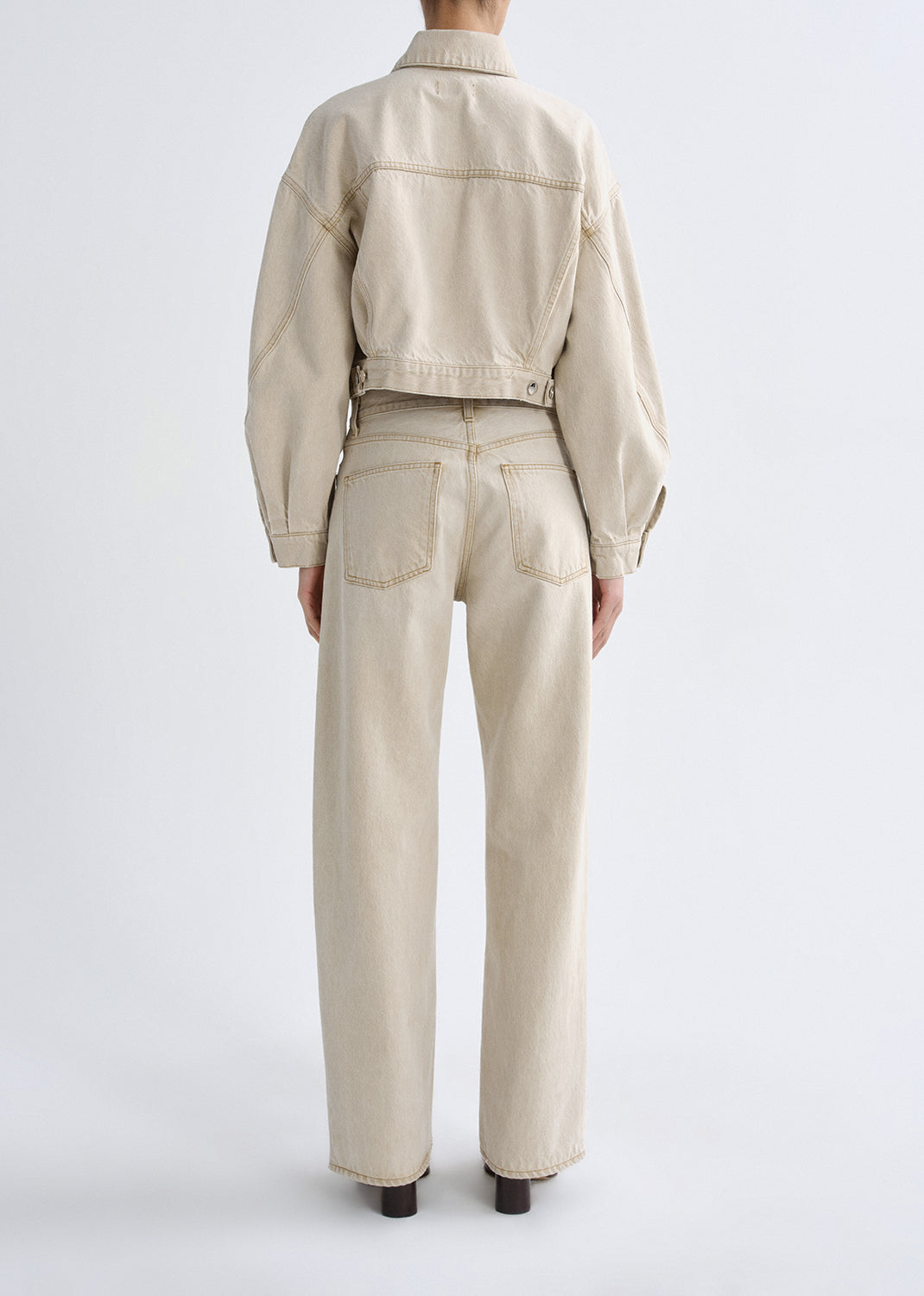 Person wearing a beige jacket and pants on a grey background