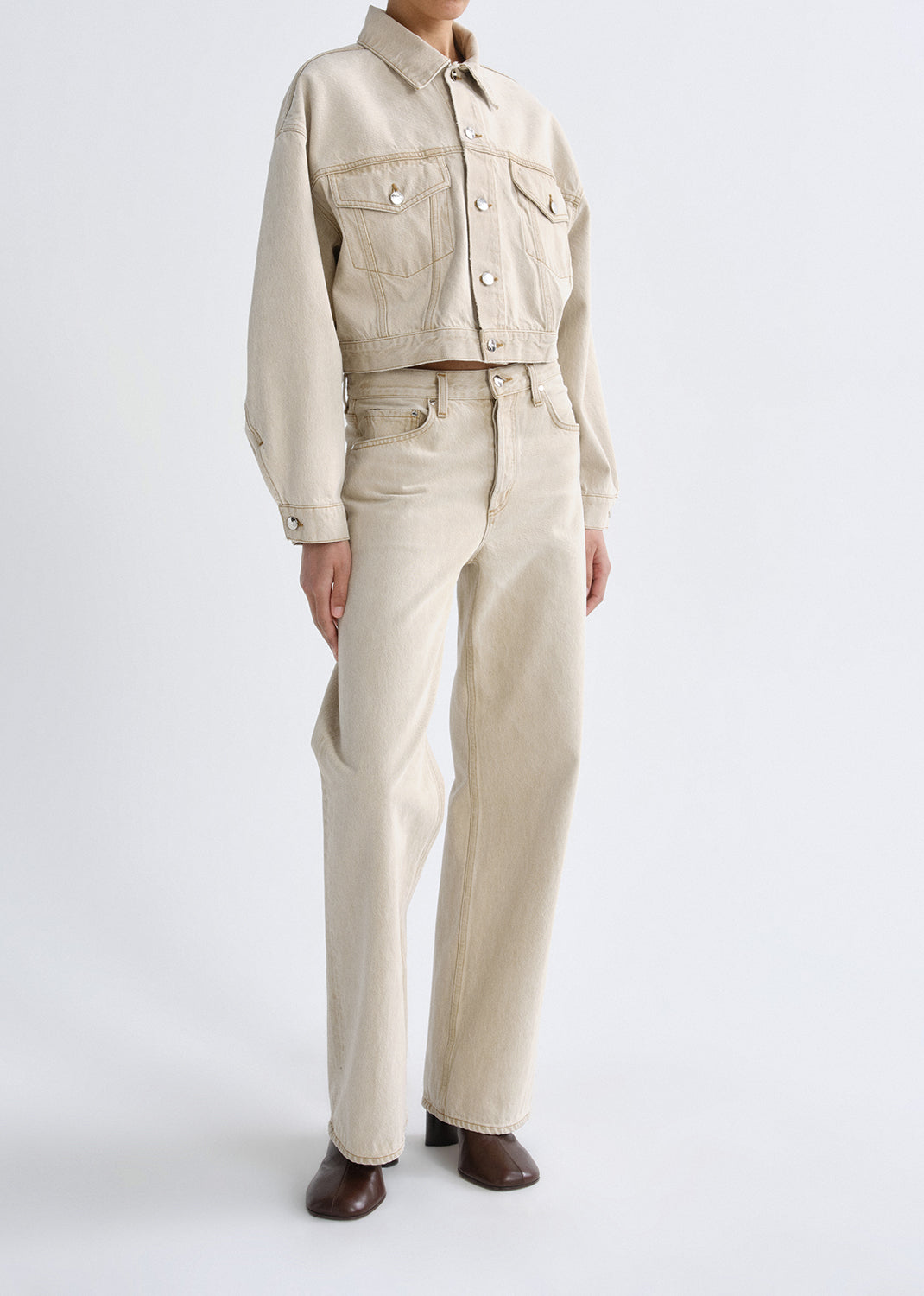 Person wearing a beige jacket and pants on a grey background