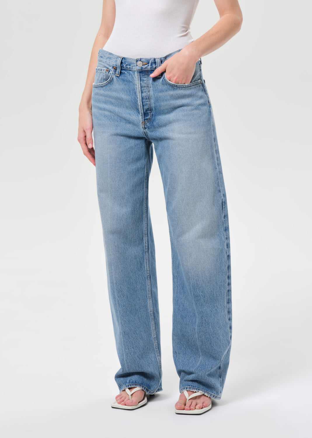 Person wearing light blue jeans on a white background