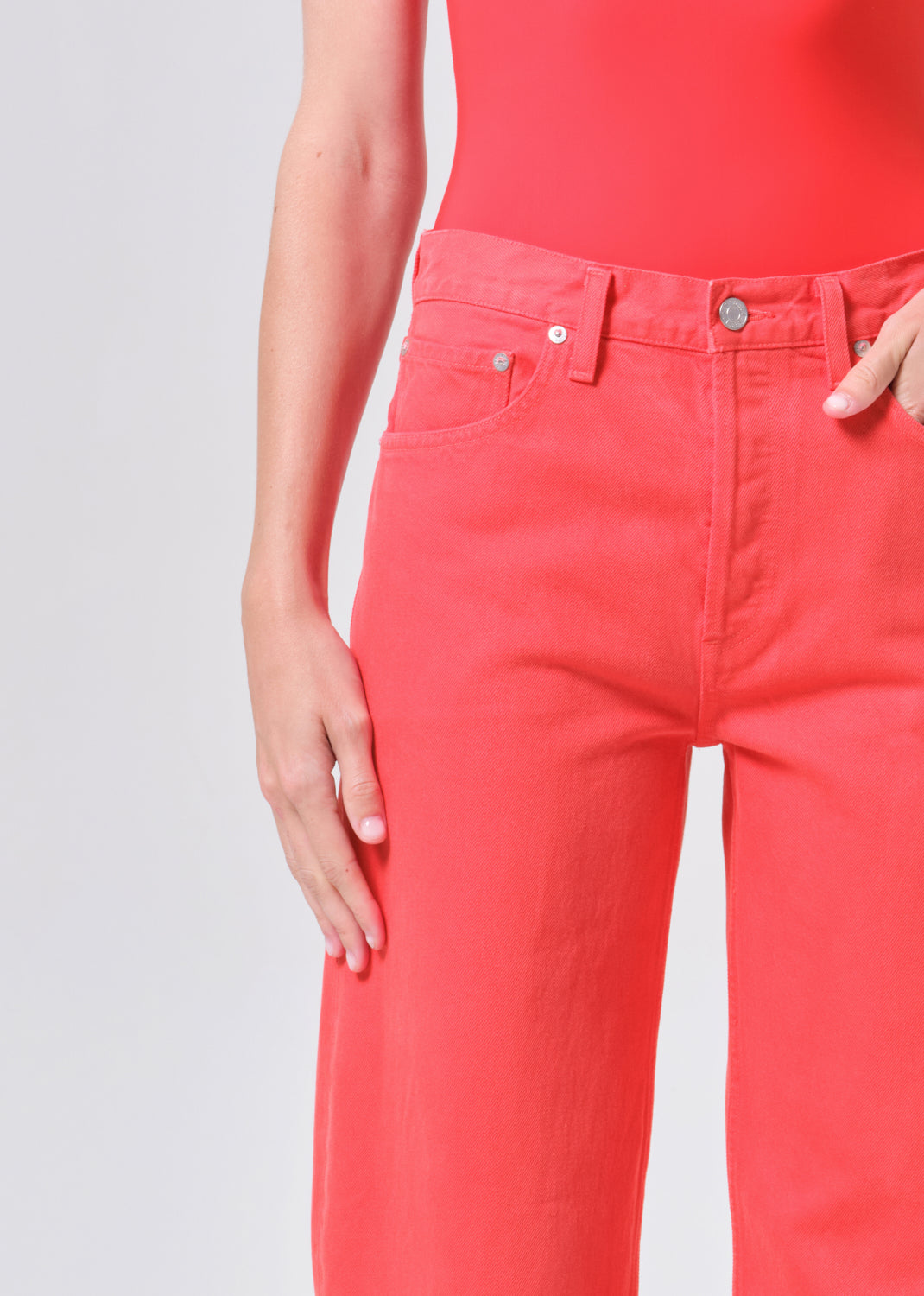 Person wearing bright red pants and a matching top on a light gray background