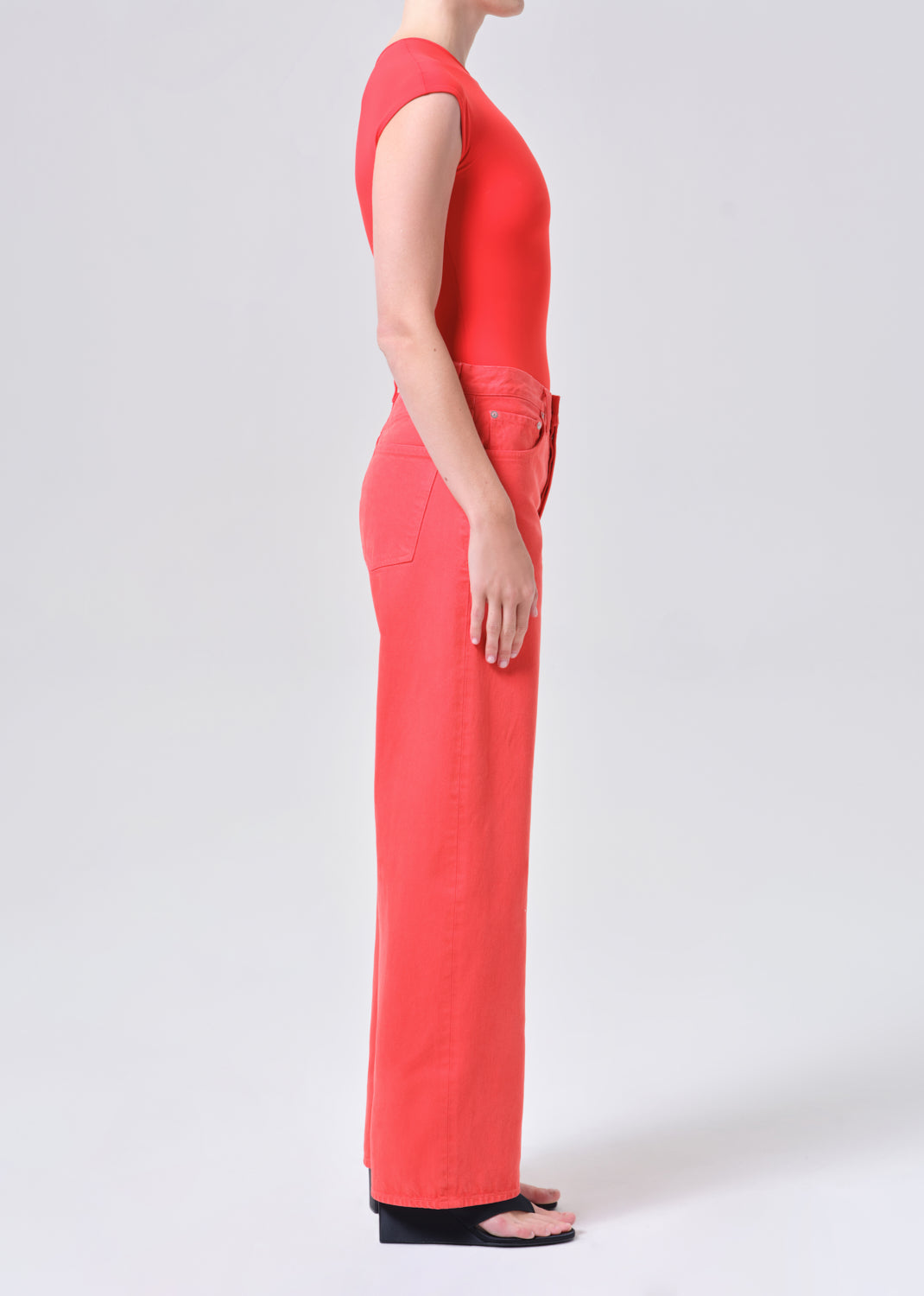 Person wearing a red sleeveless top and pants on a white background