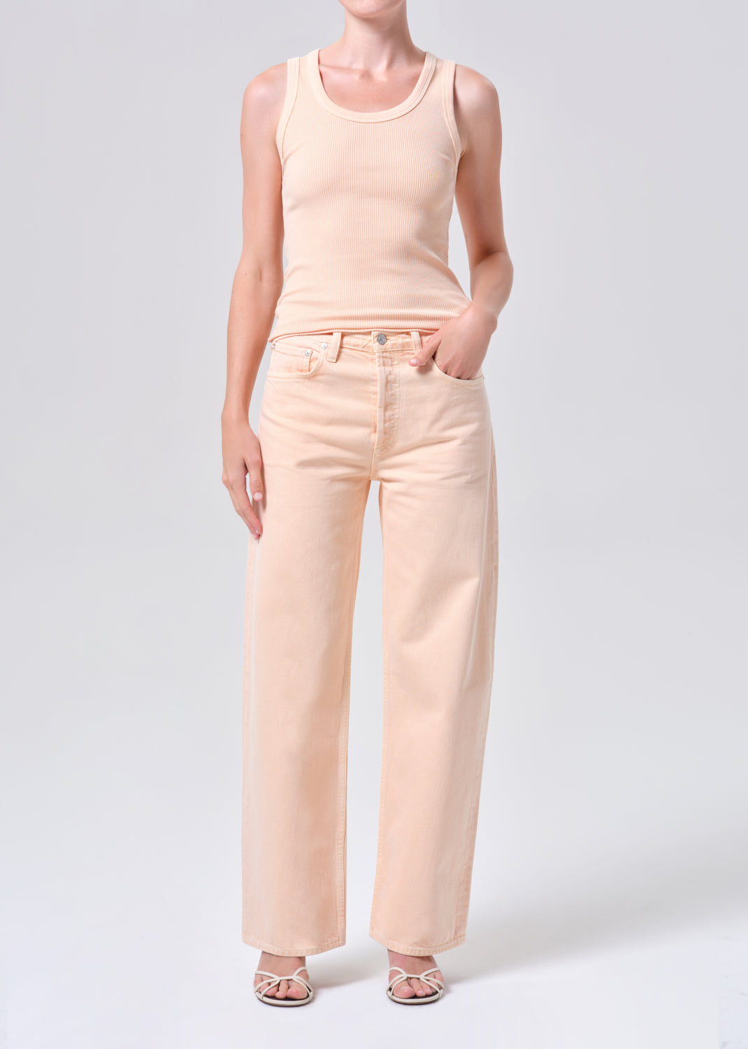 Person wearing a peach tank top and pants on a white background